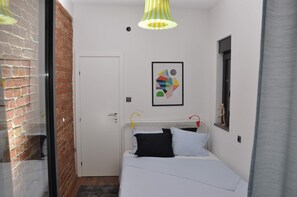 Cozy retreat with a single bed, framed artwork, and a modern light fixture.