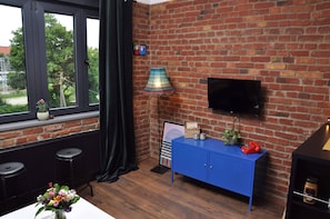 Relax in a cozy space with a brick accent wall, floor lamp, and flat-screen TV.