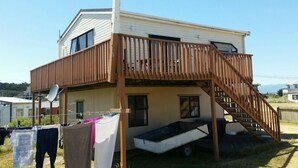 Een huis met twee verdiepingen, een houten terras en een klein bootje in de achtertuin.