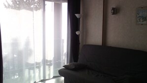 Une pièce avec un canapé, une lampe et une fenêtre avec des rideaux.