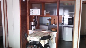 Une cuisine compacte équipée d’un four à micro-ondes, d’une machine à café et d’un petit coin repas avec une table et des chaises.