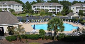 A pool area with lounge chairs and a statue, surrounded by apartment buildings. - 813 Willow Bend - Barefoot Resort Rentals (North Myrtle Beach)