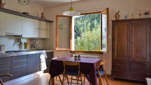 Une cuisine équipée d’une table à manger, de chaises, d’un buffet en bois et d’une fenêtre donnant sur un paysage verdoyant.