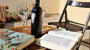 Une table en osier avec un livre, une bouteille de vin et deux verres à vin.