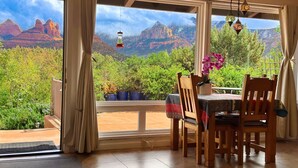 Ein Essbereich mit Tisch und Stühlen, mit Blick auf eine gebirgige Landschaft durch große Fenster, und dekorative Laternen an der Decke.