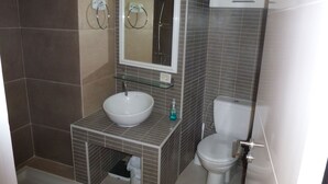 Een badkamer met een wastafel, spiegel, toilet en douchehoek.