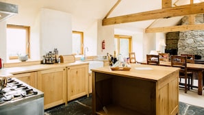 Une cuisine spacieuse avec des meubles en bois, un îlot central et une cheminée en pierre.