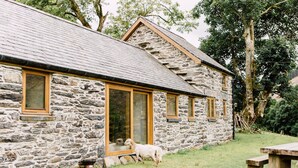 Un bâtiment en pierre doté de grandes fenêtres et d’une porte en bois.