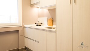 A modern kitchen with white cabinetry, a window, and a sink.