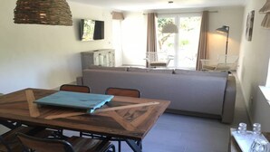 Un comedor con mesa y sillas de madera, un sofá y una ventana con cortinas.