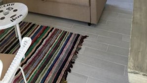 Una sala de estar acogedora con un sofá, una mesita redonda y un tapete colorido a rayas.