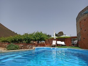 A swimming pool with lounge chairs and umbrellas, surrounded by a landscaped garden and a hillside. - PRECIOUS FINCA IN TENERIFE (Vilaflor)