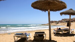 A beach with thatched umbrellas and white lounge chairs. - New villa with private pool (orihuela costa)