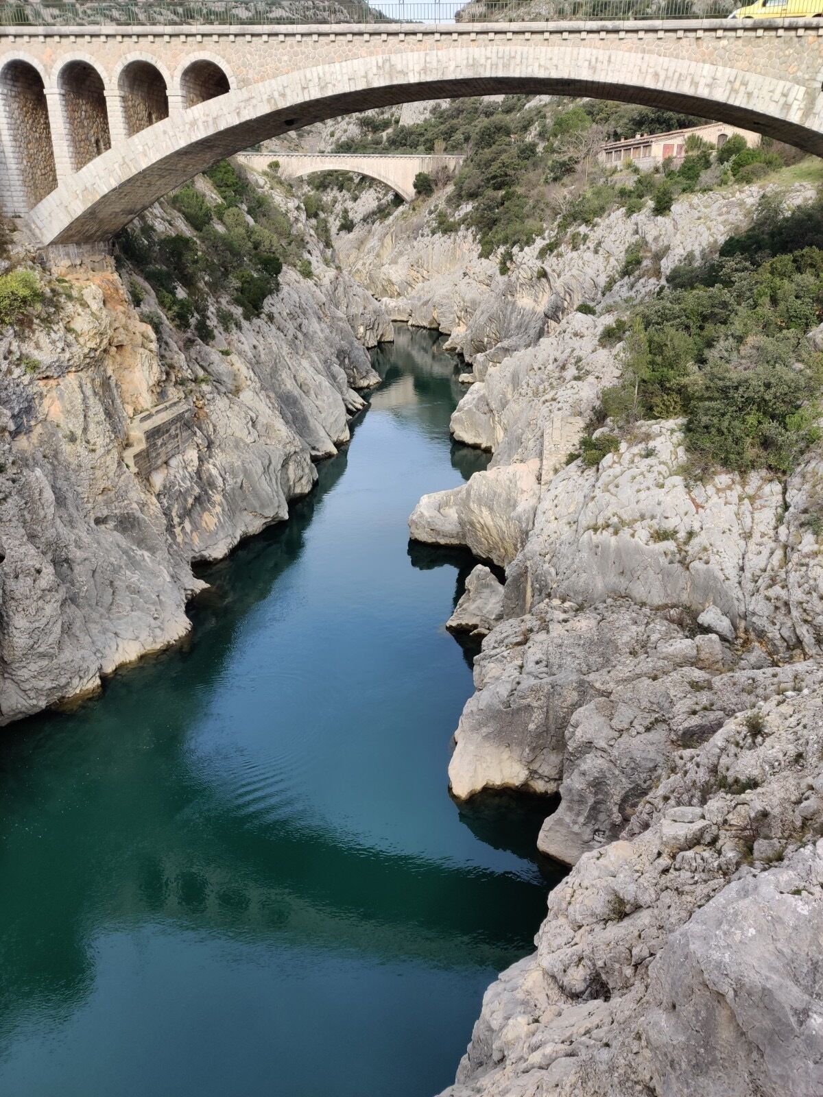 A stone bridge over a narrow canyon with a river.