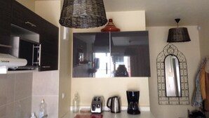 Une cuisine dotée d’un grand miroir, d’un luminaire suspendu en forme de panier et d’une machine à café.