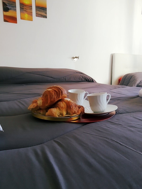 A bed with a tray of croissants and a cup of coffee on a tray.