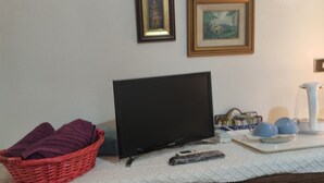 Ein Zimmer mit Fernseher, einem roten Korbwäschesystem und einem weißen Wollteppich.
