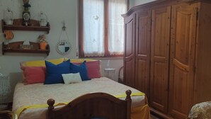 Ein Schlafzimmer mit Bett, Holzschrank und Stuhl.