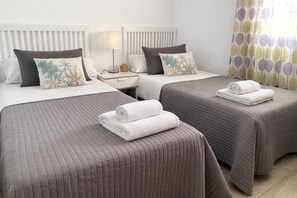 A hotel room with two beds, each with a pillow and a rolled towel.