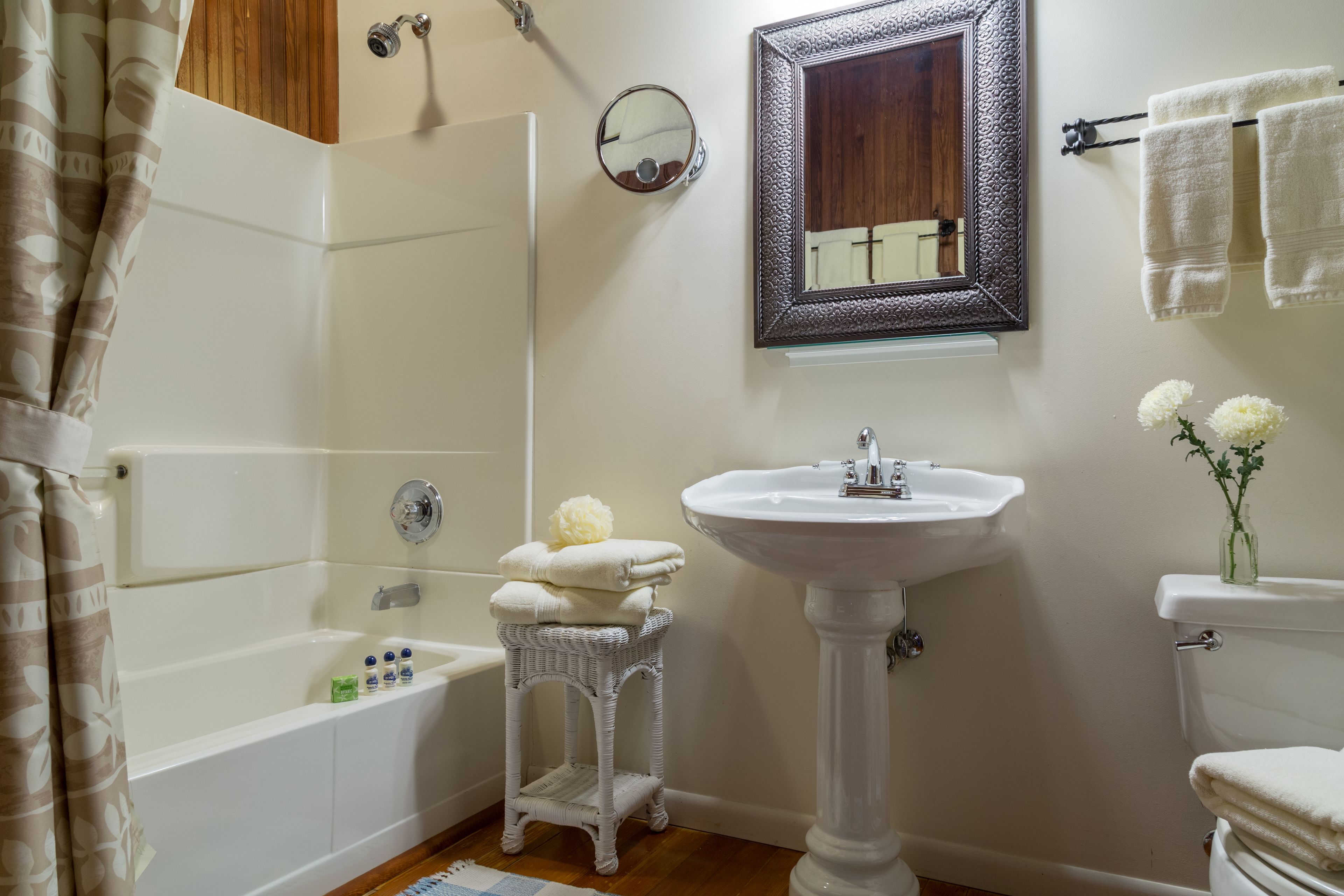 Un baño con bañera, lavamanos blanco, inodoro y espejo.