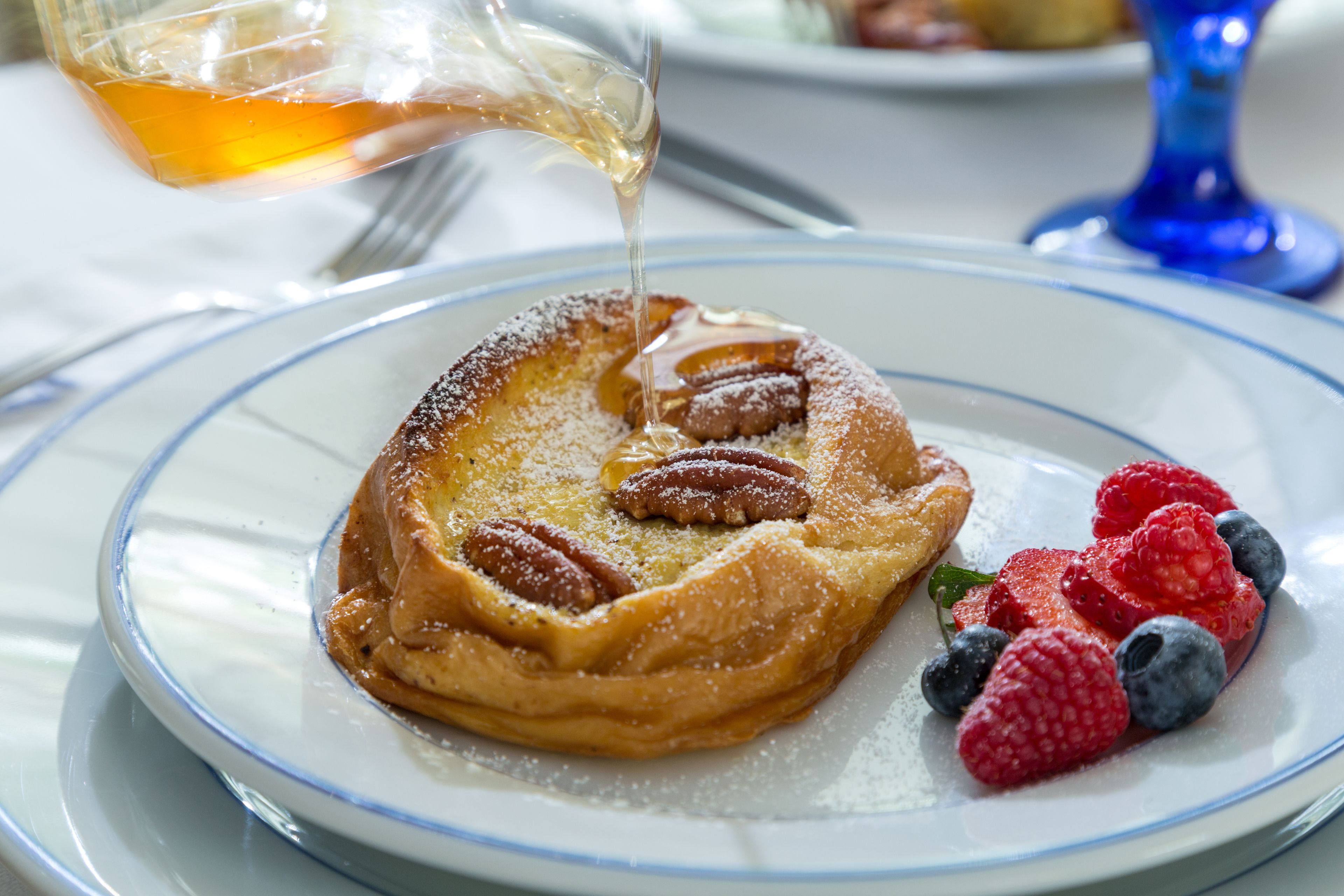 A plate with a dessert, pecans, and berries.