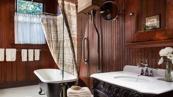 A bathroom with a bathtub, a sink, and a toilet. There are towels hanging on the wall and a window with curtains.