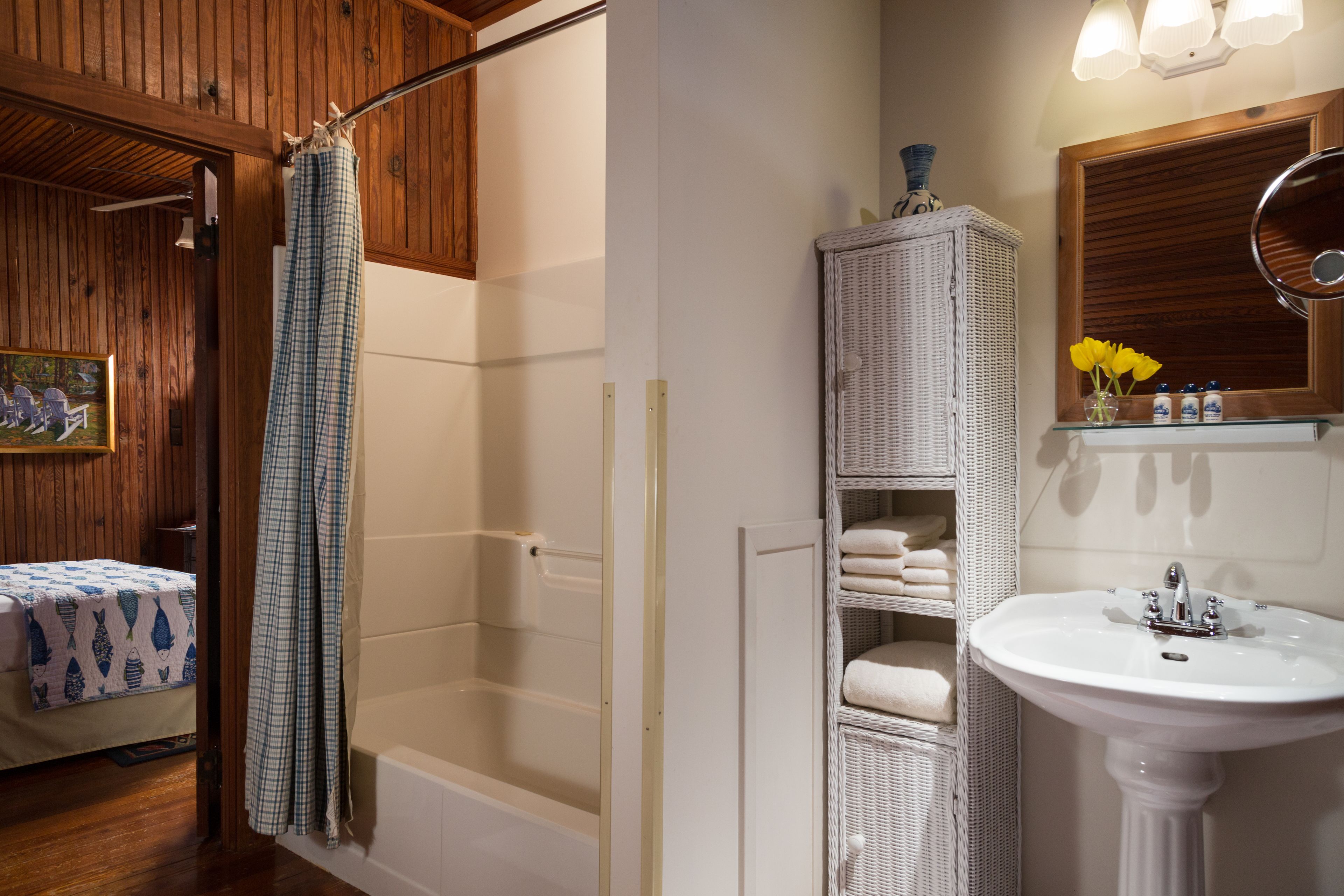 A bathroom with a bathtub, a sink, and a wicker shelf with towels.