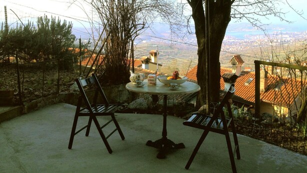 Un espacio al aire libre con una mesa y sillas, con vistas panorámicas a un pueblo y montañas.