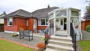 A red house with a conservatory, a front porch with a bench, and a gravel driveway. - Cedar Cottage at Rashfield nr Dunoon-sleeps up to 6-Pet Friendly(1 max) (Dunoon)