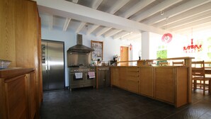 A modern kitchen with wooden cabinets, stainless steel appliances, and a large island. - Spacious farmhouse with private large heated enclosed pool and extensive grounds (Lempaut)