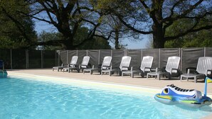 A swimming pool with clear blue water, surrounded by lounge chairs and a floating toy. - Spacious farmhouse with private large heated enclosed pool and extensive grounds (Lempaut)