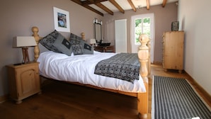 A bedroom with a wooden bed, a nightstand, a dresser, and a window with curtains. - Spacious farmhouse with private large heated enclosed pool and extensive grounds (Lempaut)