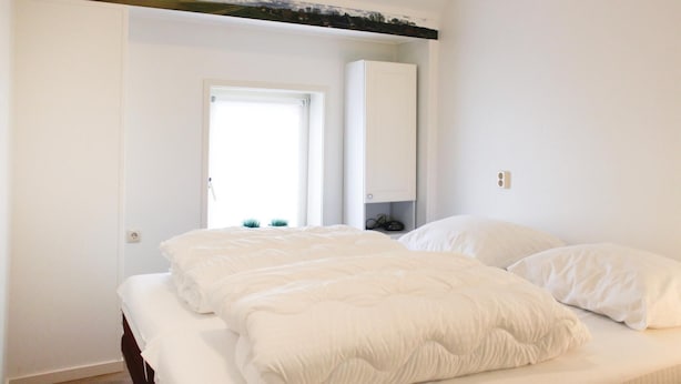 Un dormitorio con cama, armario y ventana.
