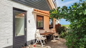 A house with a white exterior, a black door, and a patio with a table and chairs. - 1 bedroom cozy home in Sprundel (Sprundel)