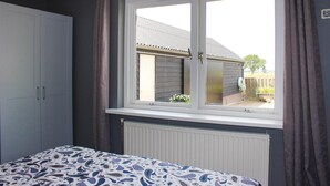 A bedroom with a large window, a wardrobe, and a radiator. - 1 bedroom cozy home in Sprundel (Sprundel)