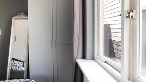 A room with a grey wardrobe, a mirror, a window with blinds, and a white sill. - 1 bedroom cozy home in Sprundel (Sprundel)
