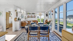 A bright, open-plan living and dining area with a large window offering a view of the sea. - 1 bedroom lovely home in Slagelse (Slagelse)