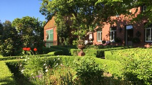 A well-maintained garden with hedges, a wooden fence, and a brick building with a green door.