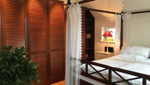 A bedroom with a four-poster bed, wooden wardrobe, and a nightstand with a lamp.