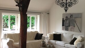 A living room with two white sofas, a wooden coffee table, a chandelier, and a painting on the wall.