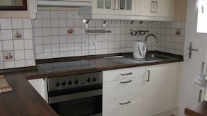 A kitchen with white cabinets, a stove, and a sink. - Cozy cottage on the vineyards (Lieser)