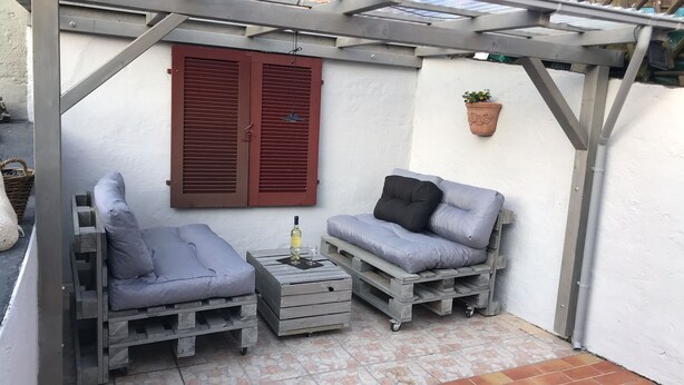 A small outdoor seating area with two gray cushioned chairs and a table, a bottle of wine, and a wine glass. - Cozy cottage on the vineyards (Lieser)