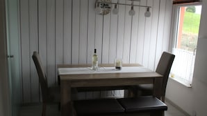 A dining table with chairs and benches, a bottle of wine, and a candle on the table. - Cozy cottage on the vineyards (Lieser)