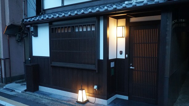 A traditional Japanese building with a wooden gate, a small illuminated lantern, and a tiled roof. - Ichijyo-Karin (Kyoto)