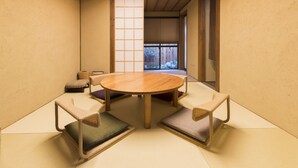 A traditional Japanese-style room with tatami flooring, a round wooden table, and low cushions. - Ichijyo-Karin (Kyoto)