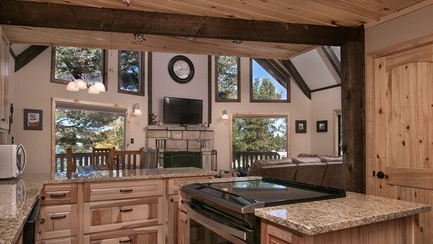 A spacious kitchen with granite countertops, wooden cabinetry, a large island, and a built-in oven.