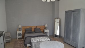 Quarto com cama, mesas de cabeceira, guarda-roupa, mesa redonda e espelho.
