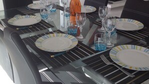 A dining table set with plates, glasses, and a bottle, surrounded by chairs. - APARTMENT 6 pers 150m SEASIDE SEA LARGE TERRACE SEA VIEW PARKING (Roquebrune-Cap-Martin)