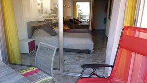A hotel room with a bed, a chair, and a view of the outside balcony. - APARTMENT 6 pers 150m SEASIDE SEA LARGE TERRACE SEA VIEW PARKING (Roquebrune-Cap-Martin)