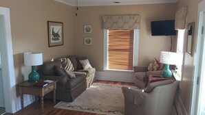 Un salon comprenant un canapé, un fauteuil, une table basse, un téléviseur et un ventilateur de plafond.